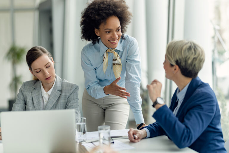 Happy African American businesswoman talking to female colleague Image description