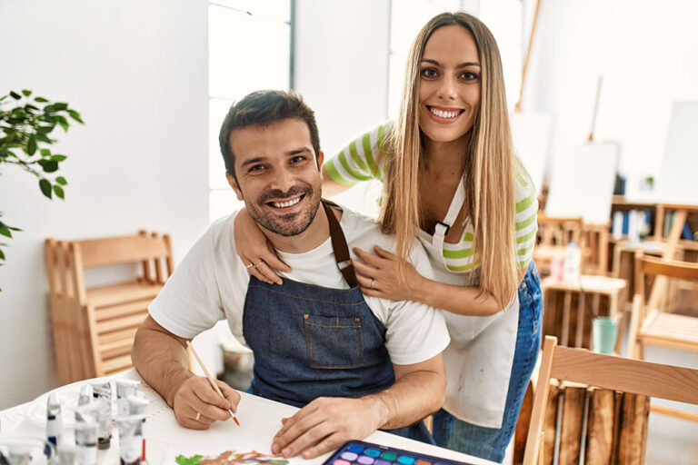 Two students smiling happy painting sitting on the table at art school Image description